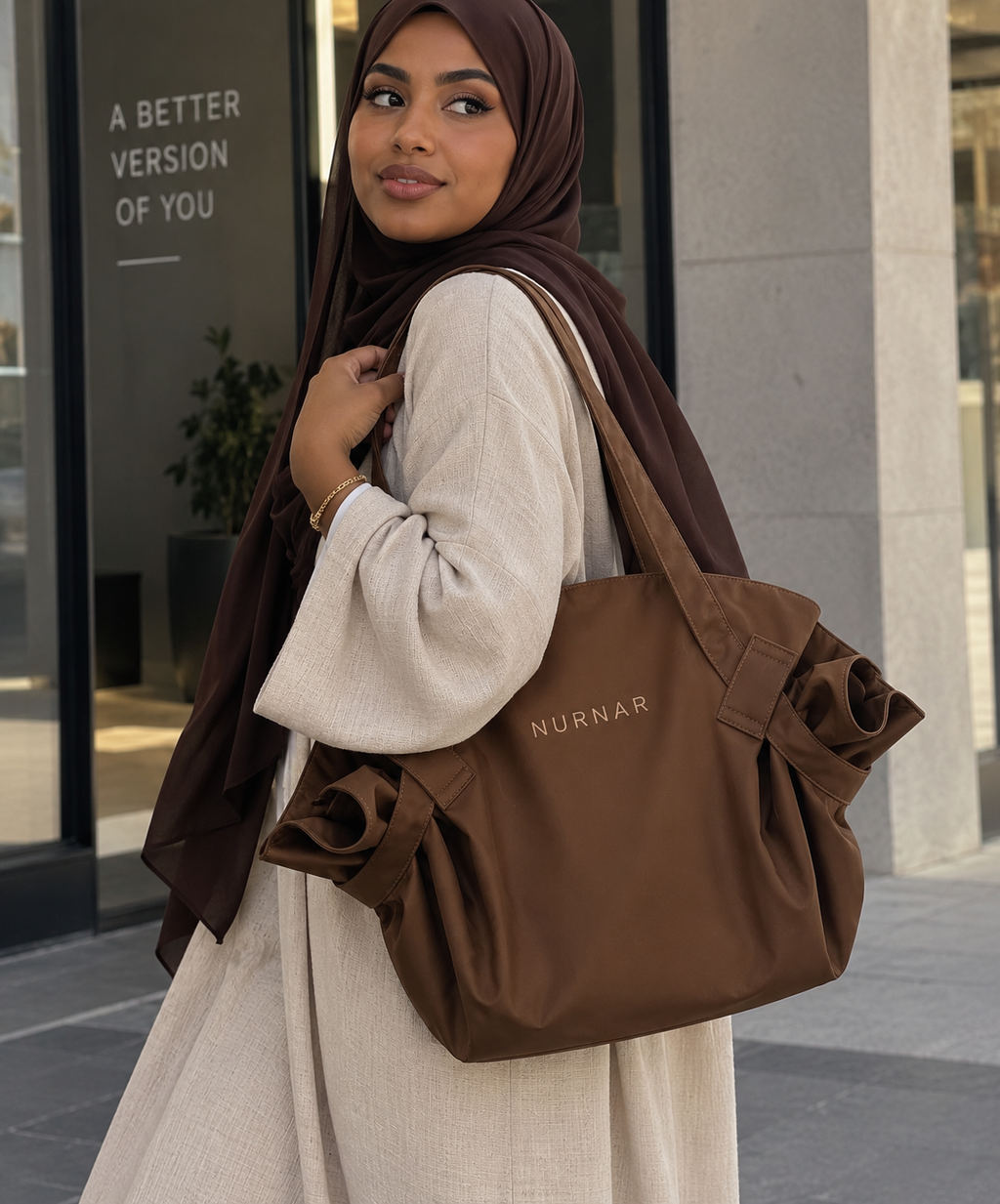 Mujer con hiyab llevando la bolsa NURNAR marrón en la ciudad